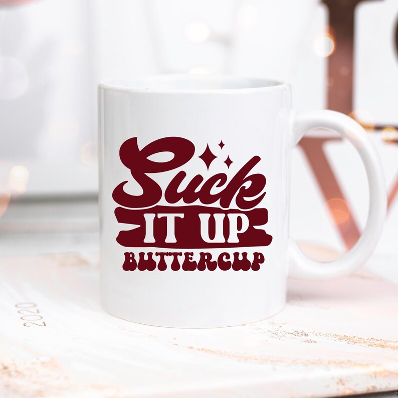 May include: White ceramic coffee mug with a burgundy red design that says "Suck It Up Buttercup".