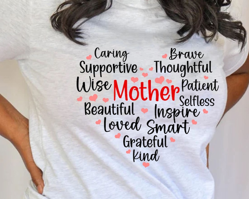 May include: White t-shirt with a heart-shaped design featuring the word "Mother" in red and a list of positive adjectives describing a mother, including caring, supportive, wise, brave, thoughtful, patient, selfless, beautiful, inspire, loved, smart, grateful, and kind.