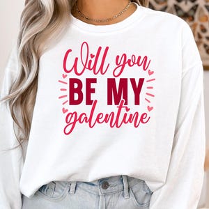 Op de afbeelding: Witte longsleeve met de tekst "Will you be my galentine" in roze letters.