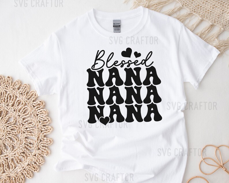 May include: White t-shirt with black text that reads "Blessed Nana Nana Nana" with a small heart graphic.
