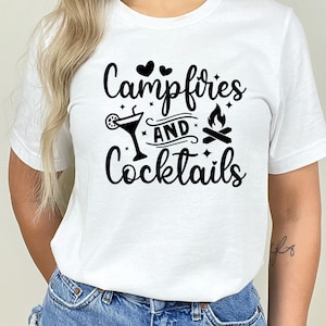 May include: White t-shirt with black text that reads "Campfires and Cocktails" with a graphic of a cocktail glass, two hearts, and a campfire.