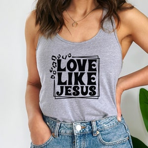 K&ouml;nnte beinhalten: Ein graues Tanktop mit dem Text "LOVE LIKE JESUS" in schwarzer, Retro-Schriftart in einem schwarzen Rahmen.