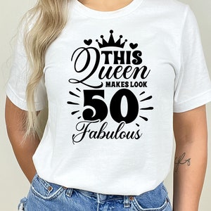 May include: White t-shirt with black text that reads "This Queen Makes Look 50 Fabulous" with a crown and hearts above the text.
