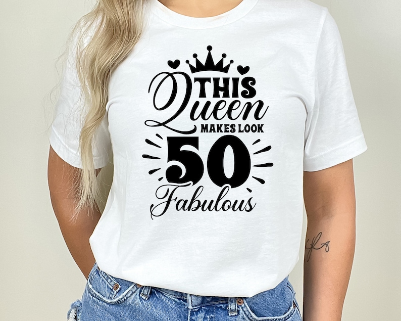 May include: White t-shirt with black text that reads "This Queen Makes Look 50 Fabulous" with a crown and hearts above the text.
