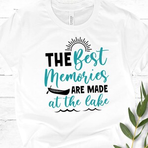 May include: White t-shirt with a teal blue graphic that says "The Best Memories Are Made at the Lake" with a sun and a canoe graphic.