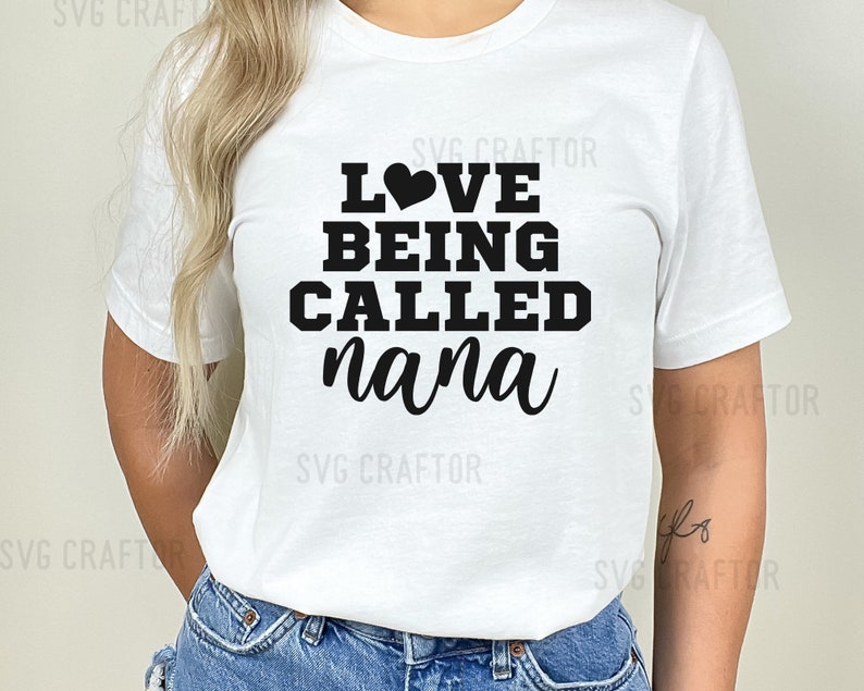 May include: White t-shirt with black text that reads "LOVE BEING CALLED nana" with a small black heart above the word "LOVE".