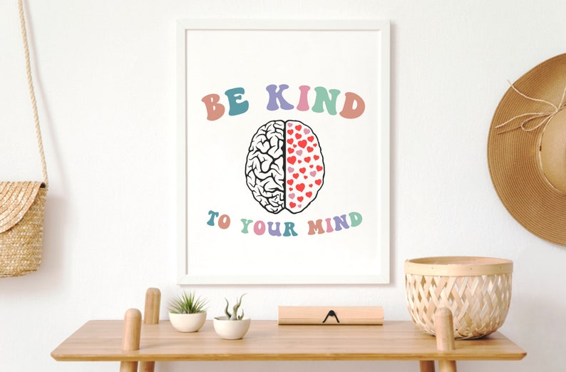 May include: A white framed print with the text "BE KIND TO YOUR MIND" in rainbow colors. A black and white illustration of a brain with one half filled with red hearts is in the center of the print.