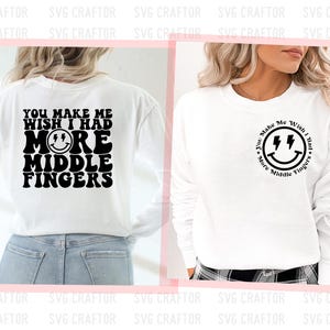 May include: White long-sleeve shirt with black text that reads "You make me wish I had more middle fingers" and a smiley face with lightning bolts for eyes. The shirt is shown on a model wearing blue jeans.
