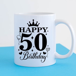 May include: White ceramic mug with a black design that says "Happy 50th Birthday" with a crown, hearts, and balloons.