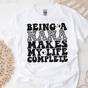 May include: White t-shirt with black text that reads "Being a Nana makes my life complete" with a heart at the end. The word "Nana" is decorated with a leopard print pattern.