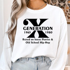 May include: White long-sleeve sweatshirt with a black graphic print of the letter X and the text "Generation 1965 1980 Raised on House Parties & Old School Hip-Hop".