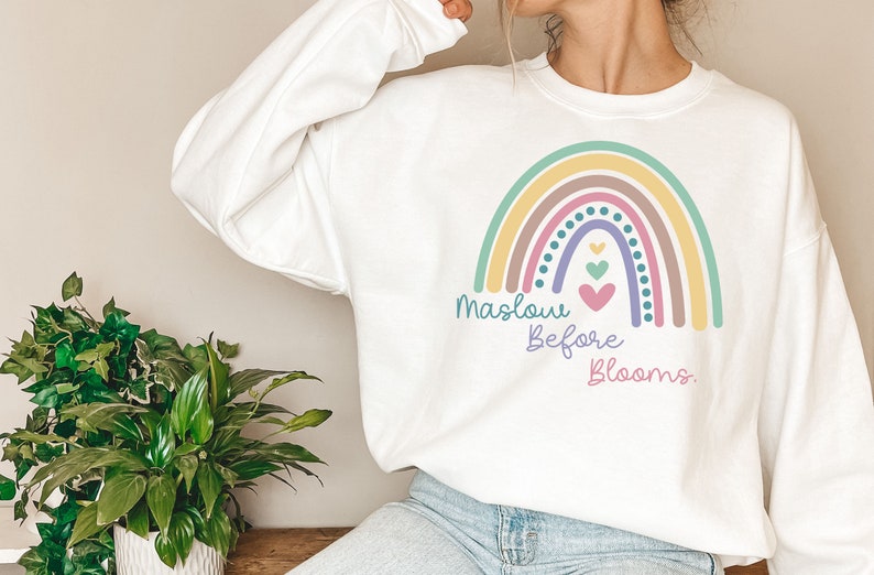 May include: White sweatshirt with a rainbow graphic and the text "Maslow Before Blooms."