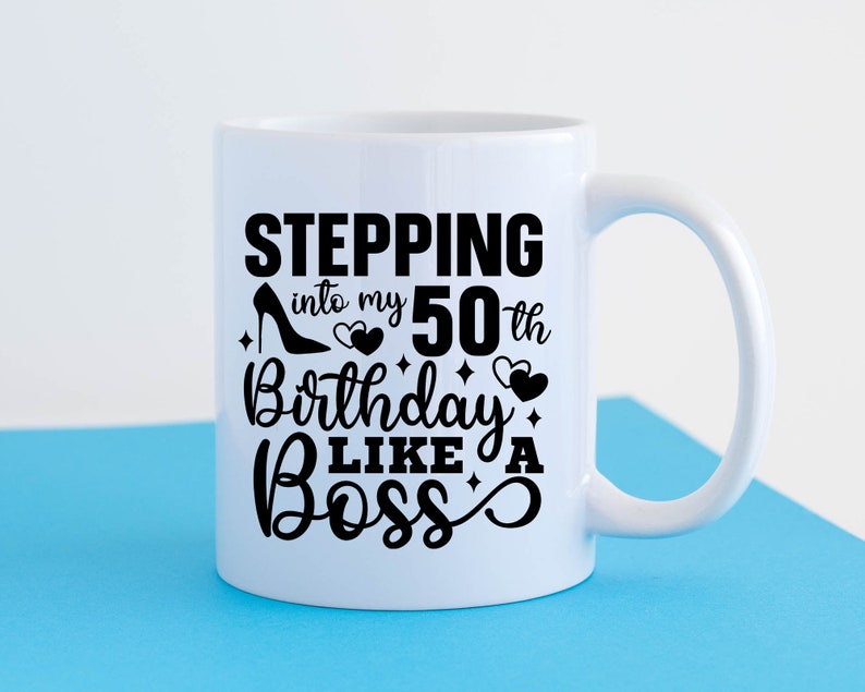 May include: White ceramic mug with a black design that says "Stepping into my 50th Birthday Like a Boss" with a high heel shoe and hearts.