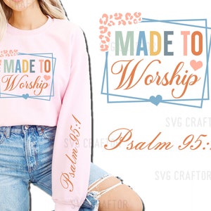 May include: Pink sweatshirt with the text "MADE TO Worship" and "Psalm 95:1" printed on it. The text is surrounded by a blue and orange frame with a heart design.