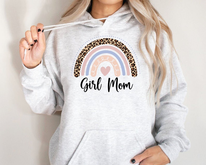 May include: A gray hoodie with a rainbow design featuring a pink, blue, and white rainbow with a leopard print border. The rainbow has a pink heart in the center and the text "Girl Mom" below it.
