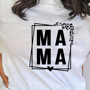 May include: White t-shirt with a black graphic that says "MAMA" in a square frame with a leopard print design and a heart at the bottom.