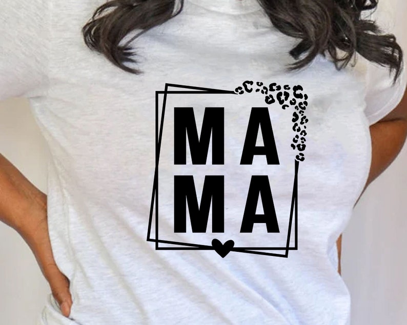 May include: White t-shirt with a black graphic that says "MAMA" in a square frame with a leopard print design and a heart at the bottom.