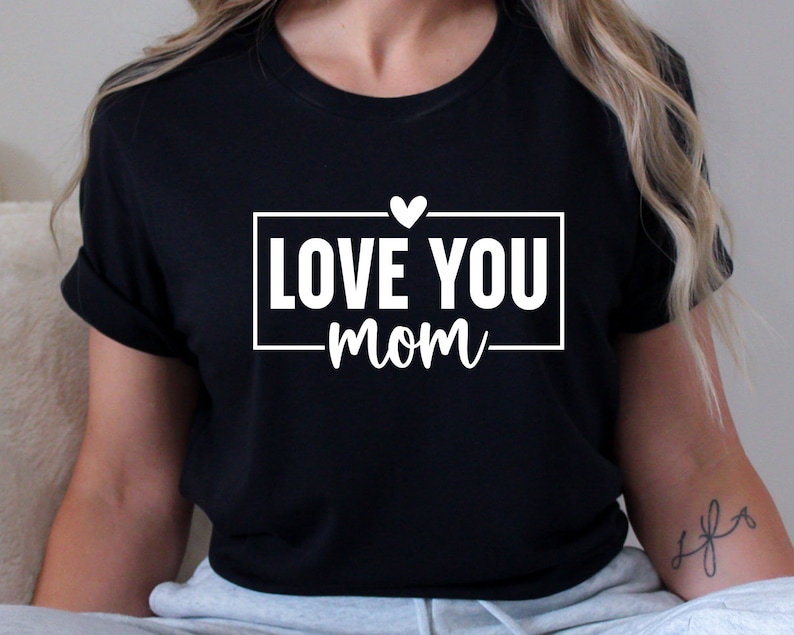 May include: Black t-shirt with white text that reads "LOVE YOU mom" with a small white heart above the text.