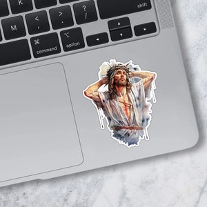 May include: A sticker featuring a watercolor painting of a man with a crown of thorns on his head. He is wearing a white robe and has a pained expression on his face.