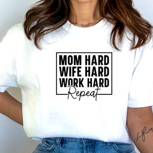 May include: White t-shirt with black text that reads "Mom Hard Wife Hard Work Hard Repeat" in a box.