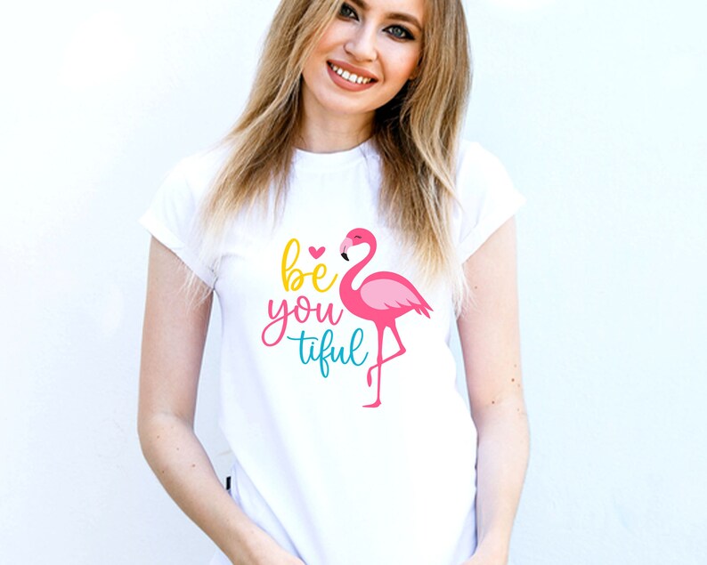 May include: White t-shirt featuring a pink flamingo and the text "be you tiful" in colourful lettering.