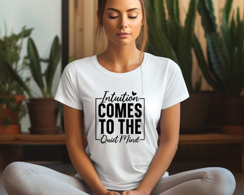 May include: A white t-shirt with a black graphic that says "Intuition comes to the quiet mind" with a small heart symbol.
