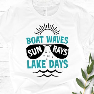 May include: White t-shirt with a teal blue graphic design that says "Boat Waves Sun Rays Lake Days". The graphic includes a sun with rays, sunglasses, and waves.