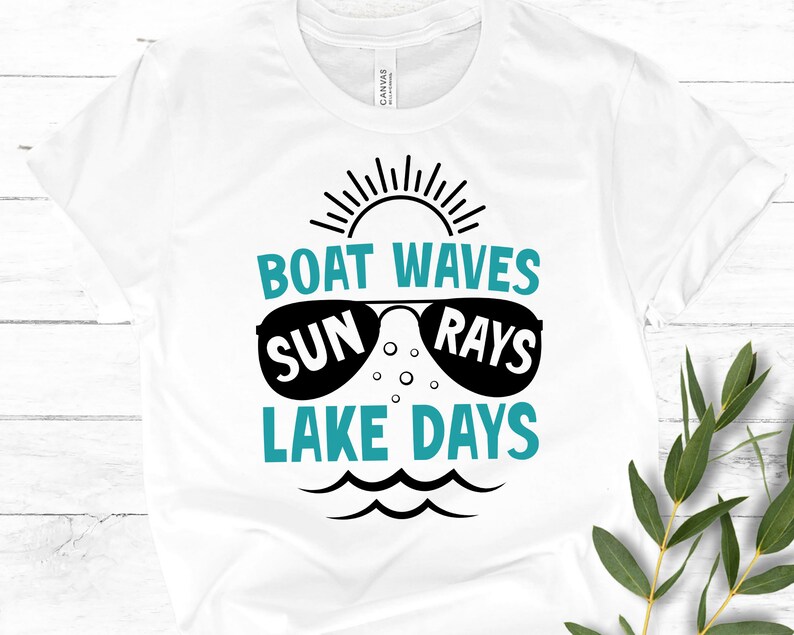 May include: White t-shirt with a teal blue graphic design that says "Boat Waves Sun Rays Lake Days". The graphic includes a sun with rays, sunglasses, and waves.