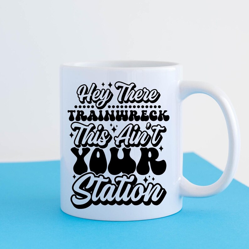 May include: White ceramic mug with a black design that says "Hey There Trainwreck This Ain't Your Station".