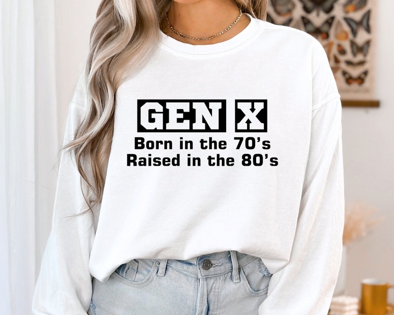 May include: White long-sleeve sweatshirt with black text that reads "GEN X Born in the 70's Raised in the 80's".
