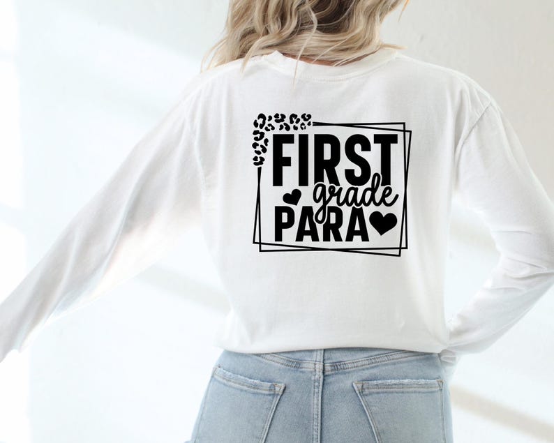 May include: White long-sleeved shirt with black text that reads "FIRST grade PARA" in a box with leopard print accents.