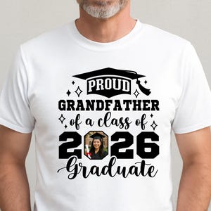 Peut inclure: T-shirt blanc avec l'inscription noire "PROUD GRANDFATHER of a class of 2026 Graduate". Le motif comprend un chapeau de graduation et une photo d'un dipl&ocirc;m&eacute;. Le t-shirt est port&eacute; par une personne.