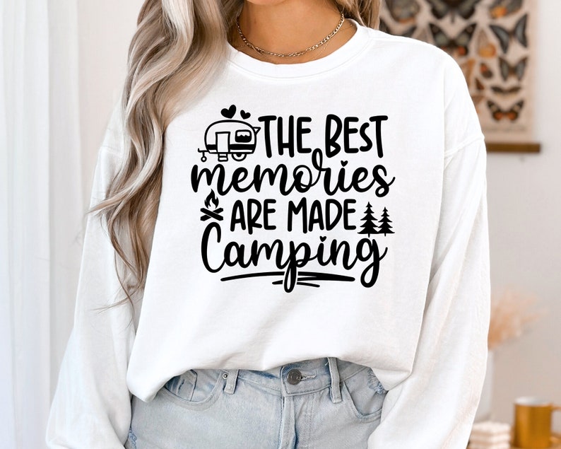 May include: White long-sleeve shirt with black text that reads "The Best Memories Are Made Camping" with a camper, campfire, and trees graphic.