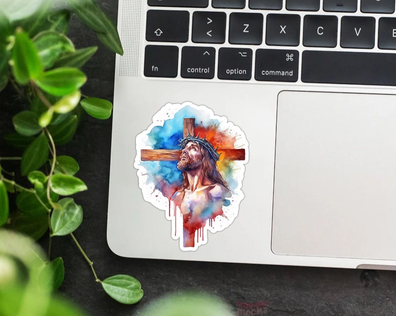 May include: A watercolor painting of Jesus Christ on the cross. The painting is in shades of blue, red, and orange, with splashes of white paint. Jesus is wearing a crown of thorns and has a pained expression on his face.