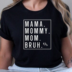 May include: Black t-shirt with white text that reads "Mama. Mommy. Mom.  Bruh." with a small heart symbol.