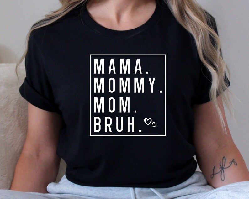 May include: Black t-shirt with white text that reads "Mama. Mommy. Mom.  Bruh." with a small heart symbol.