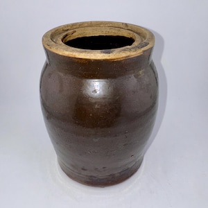 May include: A white ceramic mug with a black handle and the text "But First, Coffee" in a black, handwritten-style font. The mug is on a white surface.