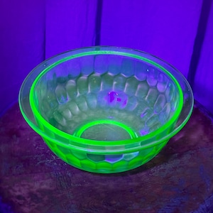 Puede incluir: Un par de cuencos de vidrio anidados con un tono verde neón brillante. Los cuencos tienen un patrón texturizado, similar a un panal, en los lados. Los bordes y las bases de los cuencos están delineados en un verde vibrante. Los cuencos están sobre una superficie oscura.