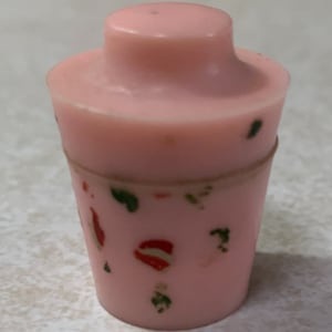 May include: A pink plastic shaker with a lid and a colorful floral design.