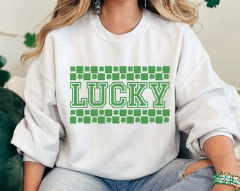 May include: White sweatshirt with a green shamrock pattern and the word "LUCKY" in a green block font.