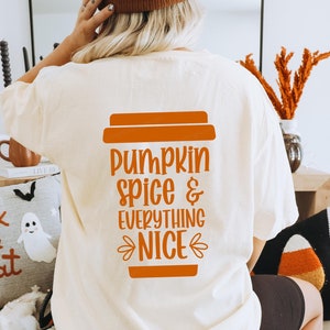 Peut inclure: Un t-shirt blanc avec un graphique orange d'une tasse de café et le texte "pumpkin spice & everything nice".