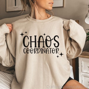 May include: A beige sweatshirt with the text "Chaos Coordinator" in black lettering and small star accents.