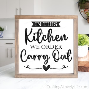 Puede incluir: Un letrero de madera blanco con una inscripción negra que dice "En esta cocina pedimos para llevar" con un pequeño corazón negro en la parte inferior.