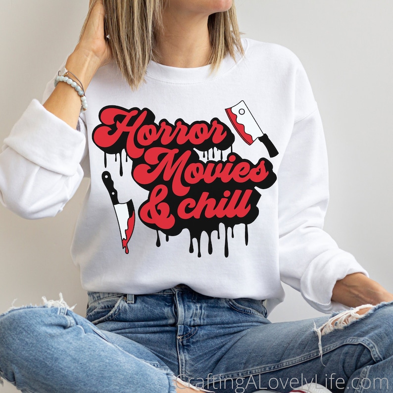 May include: White sweatshirt with a black and red graphic that says "Horror Movies & Chill" with dripping black paint and a red knife and a red cleaver.