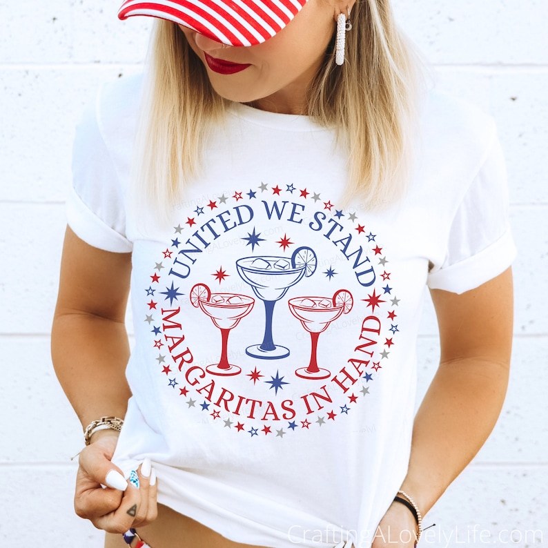 May include: White t-shirt with a red, white, and blue circle design featuring three margarita glasses and the text "United We Stand Margaritas In Hand".