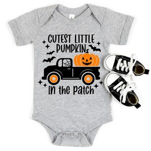 May include: A gray baby onesie with the text "Cutest Little Pumpkin in the Patch" and a black truck carrying a jack-o'-lantern.