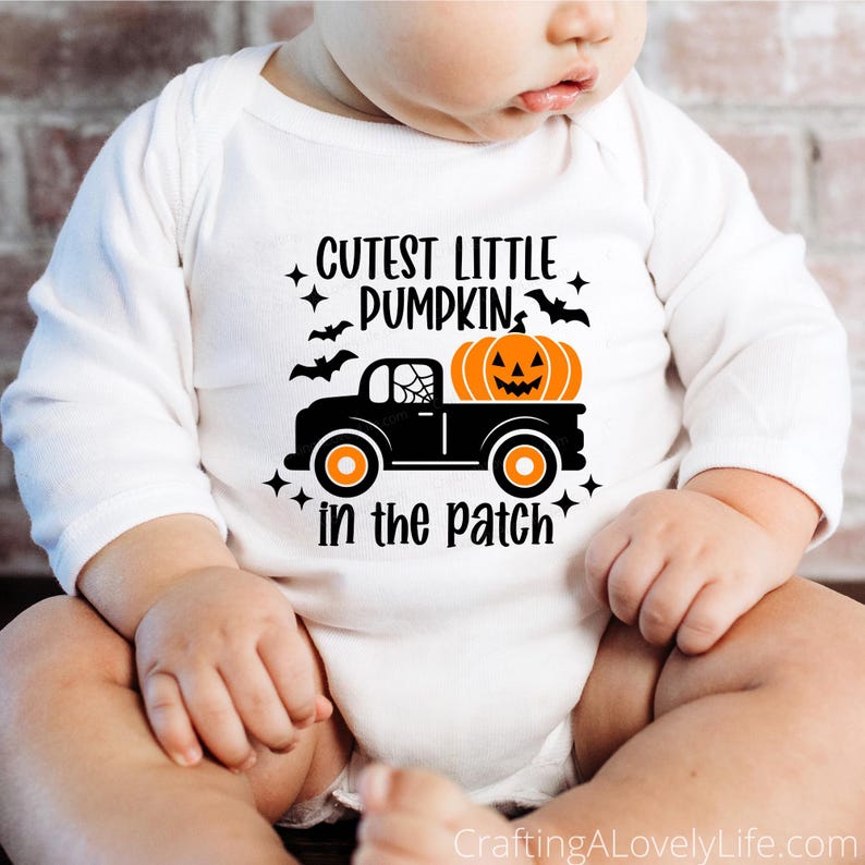 May include: A white long-sleeved onesie with the text "Cutest Little Pumpkin in the Patch" and a black truck with a jack-o-lantern in the bed.