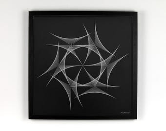 Op de afbeelding: Een ingelijst kunstwerk met een geometrisch ontwerp in wit op een zwarte achtergrond. Het vierkante kunstwerk heeft een centraal cirkelvormig patroon met uitstralende lijnen, alles in een zwart frame. Het hangt aan een witte muur.