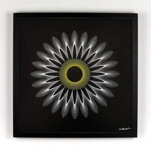 May include: A framed artwork featuring a geometric design resembling a flower. The artwork has a black background with a central yellow circle and white radiating lines, all within a black frame. The piece is signed in the lower right corner.