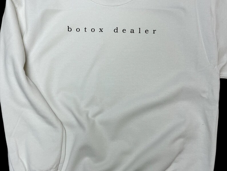 May include: White sweatshirt with the text "botox dealer" printed on the front.